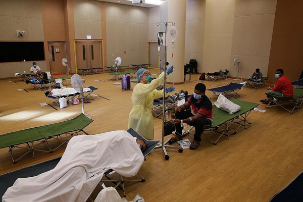  ​In a photo from April 28, 2020, a nurse attends to a migrant worker on drip at Jurong Community Hospital.PHOTO ST FILE