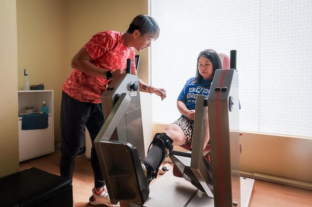  ​ActiveSG Instructor Victor Ng, 51, helps stroke survivor Maya Seah, 44, as she works on strengthening her legs at the Enabling Village ActiveSG Gym on Dec 19.ST PHOTO GAVIN FOO 
